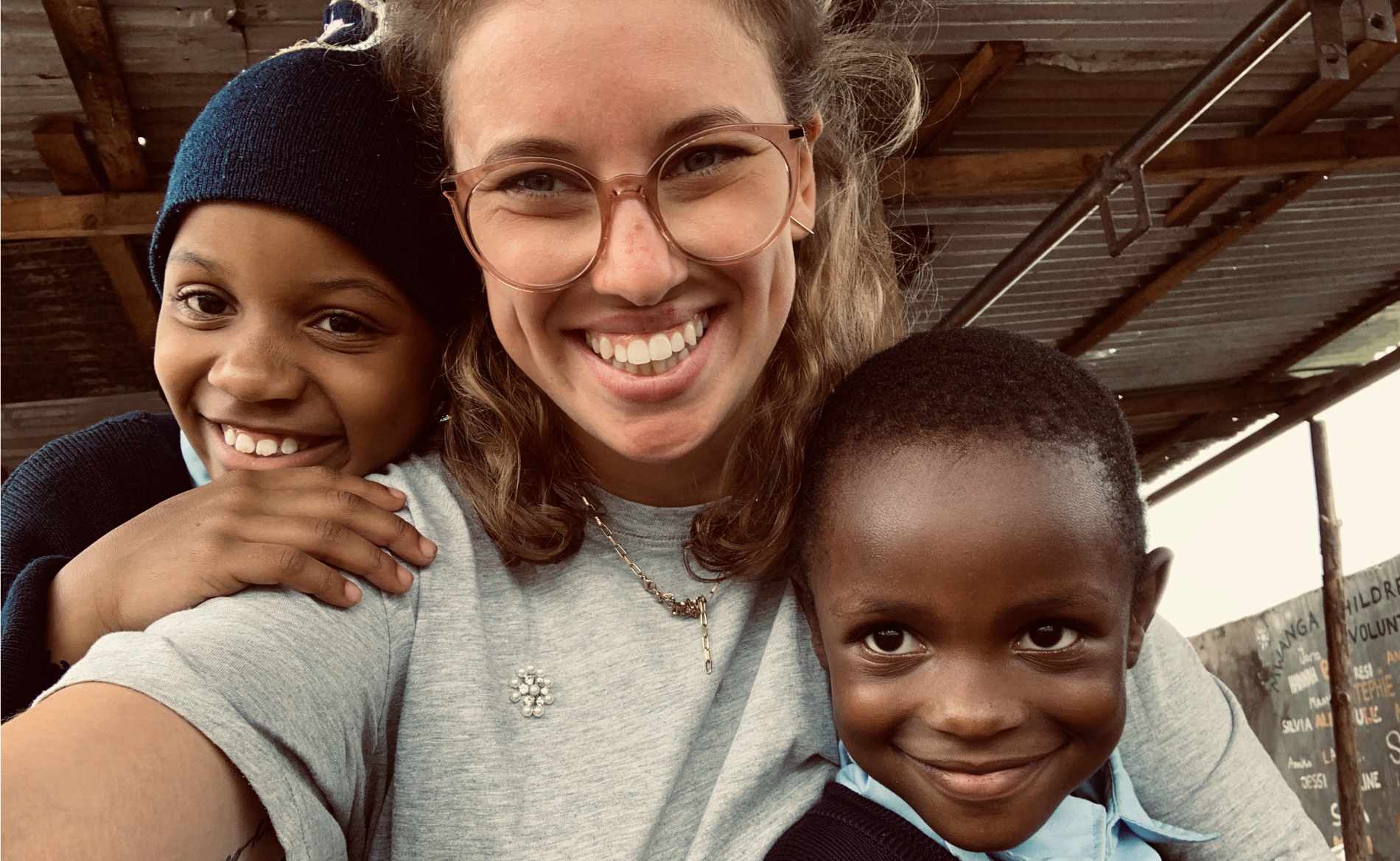 Eine Freiwillige lächelt mit zwei Kindern in die Kamera