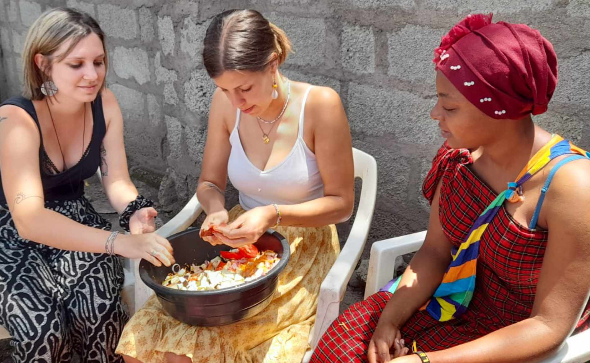 Zwei Freiwillige bereiten mit einer Tansanierin das Essen vor